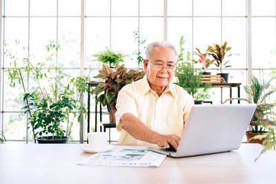A senior man using a laptop in a bright indoor space