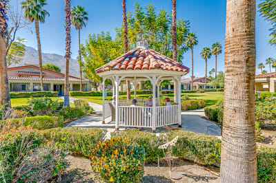 Residents enjoying time in a gazebo surrounded by gardens