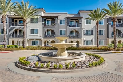 A courtyard with a fountain and palm trees in front of the building