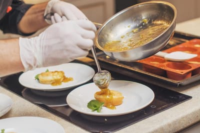 A chef plating a dessert in a dining area