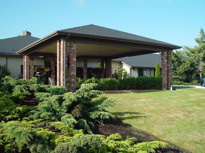 Covered outdoor area with landscaping in front of a senior living facility