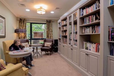 Resident reading in a cozy library setting