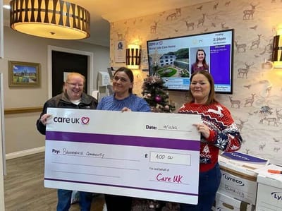 Residents and staff holding a big check in a decorated lobby