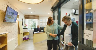 Staff assisting a resident at the entrance of the facility
