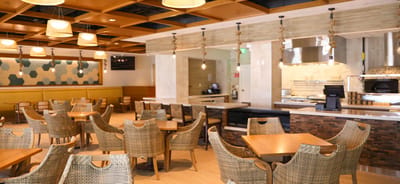 A spacious dining area with wooden tables and woven chairs