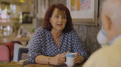 A woman engaging in conversation over coffee in a common area