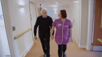 Staff member walking with a resident in the hallway