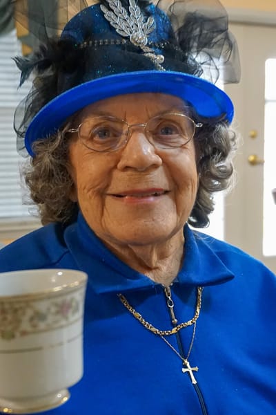 Senior woman in a blue outfit and hat, smiling