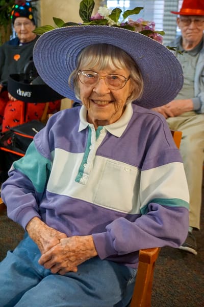 Resident smiling with a large sunhat in a common area