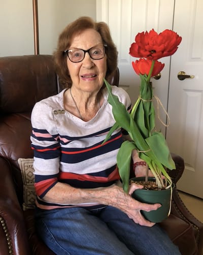 Resident holding a potted flower in a cozy chair