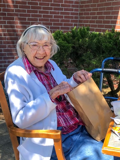 Senior woman smiling while holding a paper bag outdoors