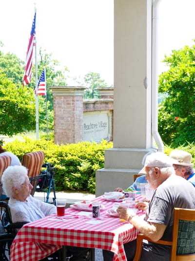 Residents enjoying lunch outdoors with a view of Peachtree Village