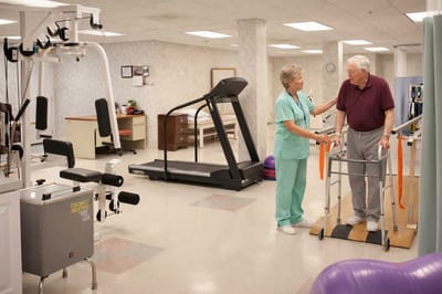 A staff member assisting a resident in a therapy room
