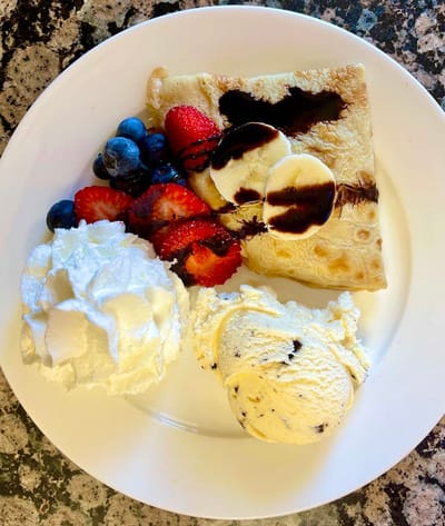 Dessert plate with crepes, ice cream, and fruit