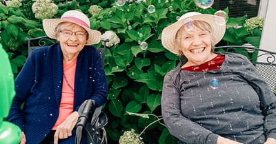 Two seniors smiling outdoors with hats