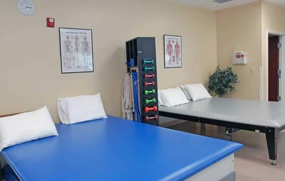 Therapy room with exercise equipment and beds.