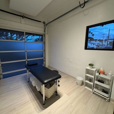 Physical therapy room with treatment table and rolling cart.