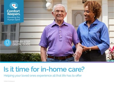 A caregiver assisting a senior man outdoors.