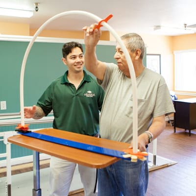 Staff assisting a resident with mobility training equipment