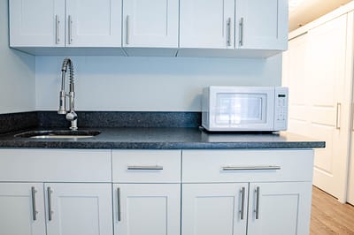 Modern kitchenette with white cabinets and microwave