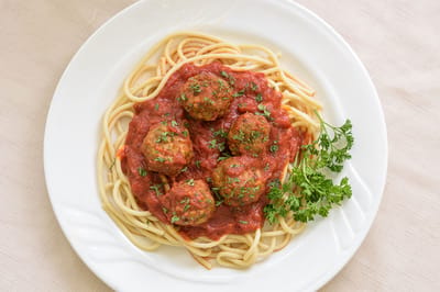 A plate of spaghetti and meatballs with parsley
