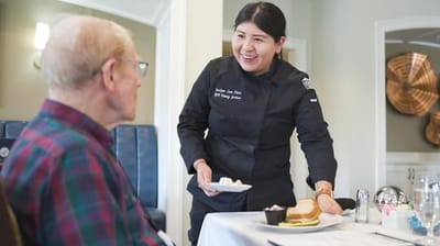 Staff serving food to a resident in the dining room
