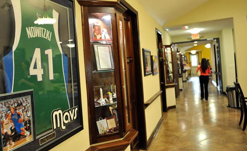 A hallway with framed memorabilia and a resident walking