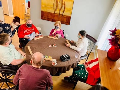 Residents engaged in a card game around a table.