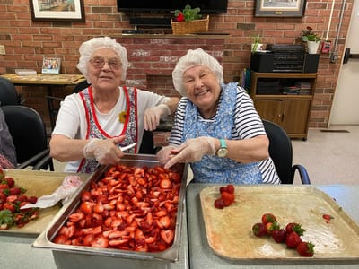 Two residents joyfully preparing strawberries.