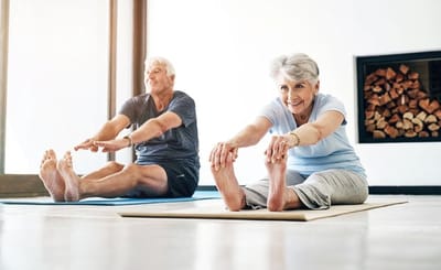 Two seniors stretching in a fitness class