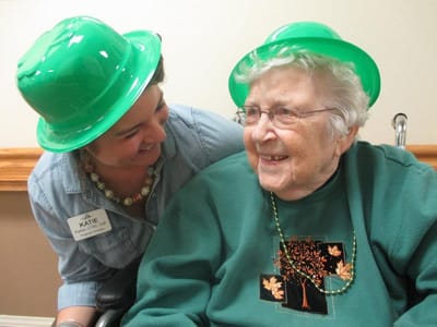 Staff member and resident celebrating with green hats