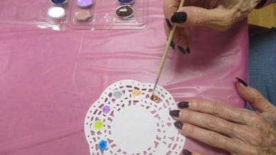Resident painting on a doily during an art activity