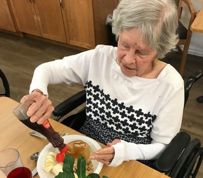 Resident enjoying pancakes with syrup in the dining area.