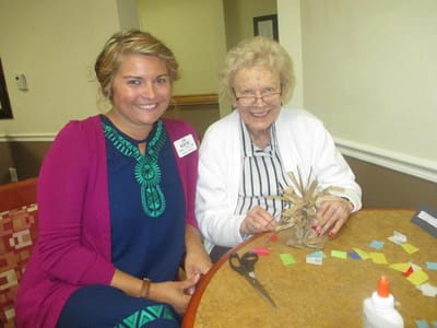 Staff member helps a resident with a craft project