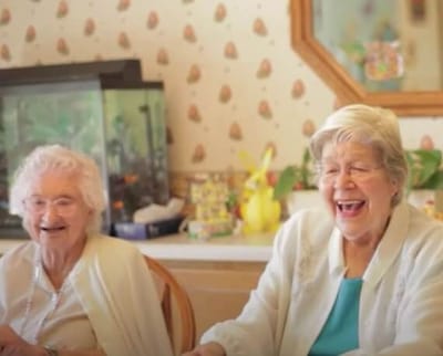 Two elderly women laughing together in a communal area