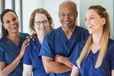 Four healthcare professionals smiling and interacting in a facility