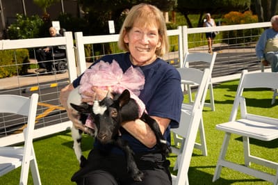 Resident holding a goat in an outdoor setting