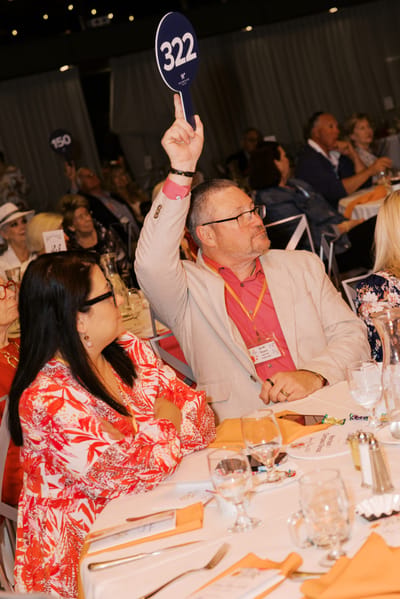 Participants at a lively event, holding numbered paddles