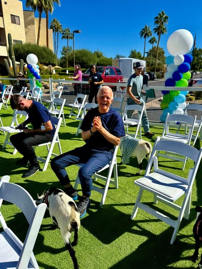 Residents interacting with goats in a festive outdoor setting