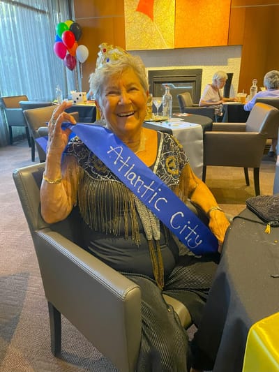 Resident celebrating with a sash in a festive setting