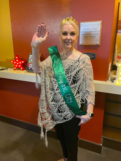 Resident celebrating in a common area with a sash and crown
