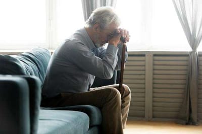 Senior man sitting on a couch with a cane