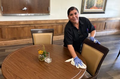 Staff member cleaning a table in the dining area.