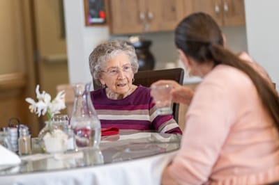 Two residents engaged in conversation at a dining table.