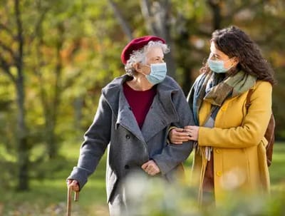 Senior woman walking with a caregiver outdoors