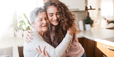 A woman embracing an elderly resident in a warm setting.