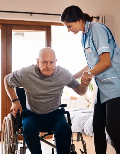 Healthcare worker assisting an elderly man in a wheelchair.