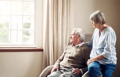 Two residents engaging by a window in a common area.