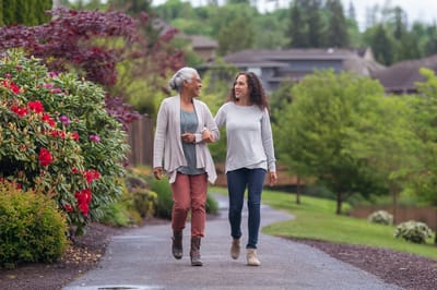 Two women walking together in a garden