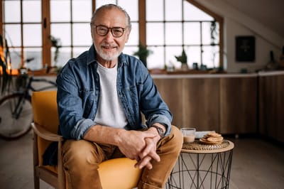 Smiling elderly man sitting in a cozy interior